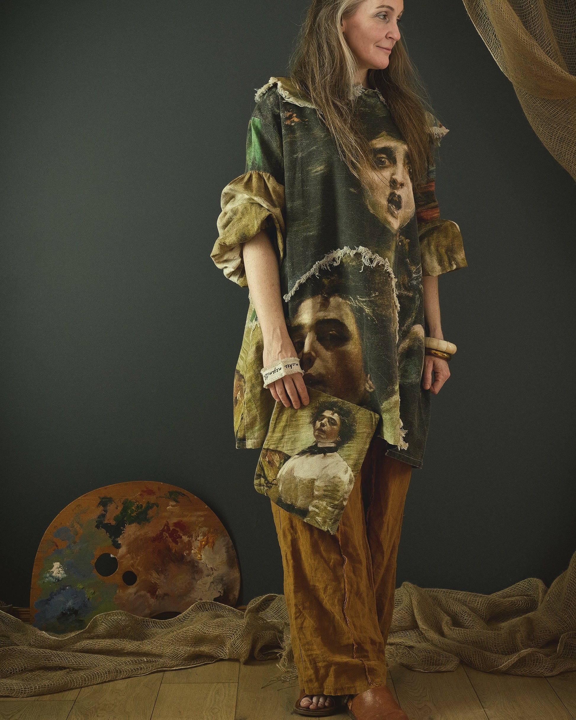 Person wearing a unique, layered outfit with artistic elements in a studio setting.